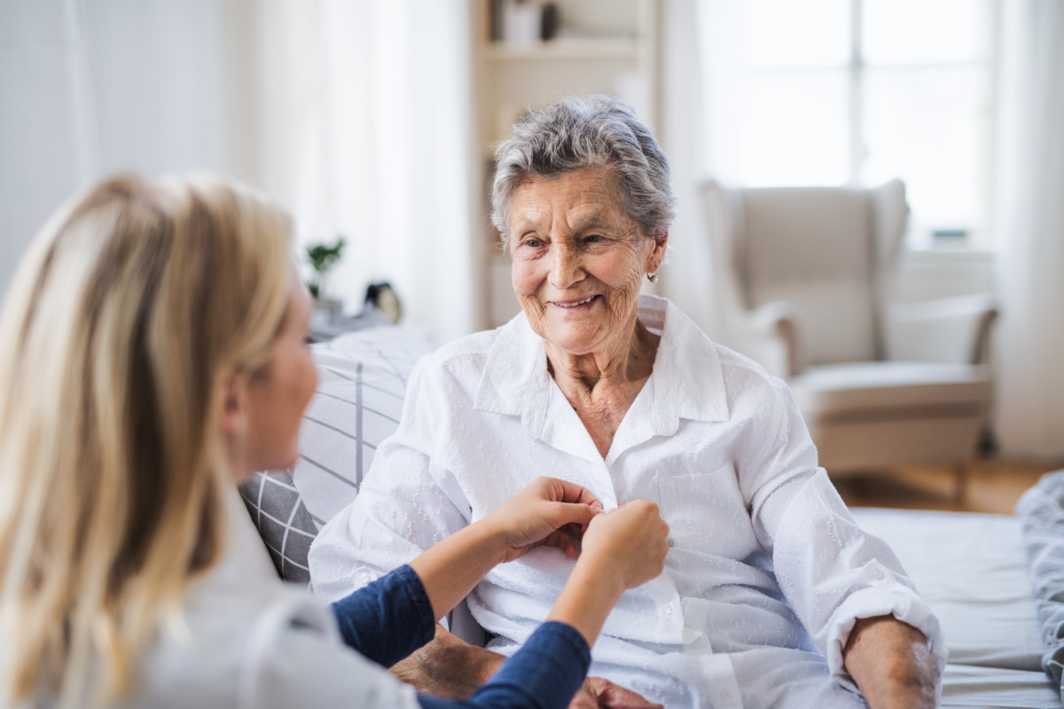 A caregiver and an older adult sharing a warm moment in a bright home
